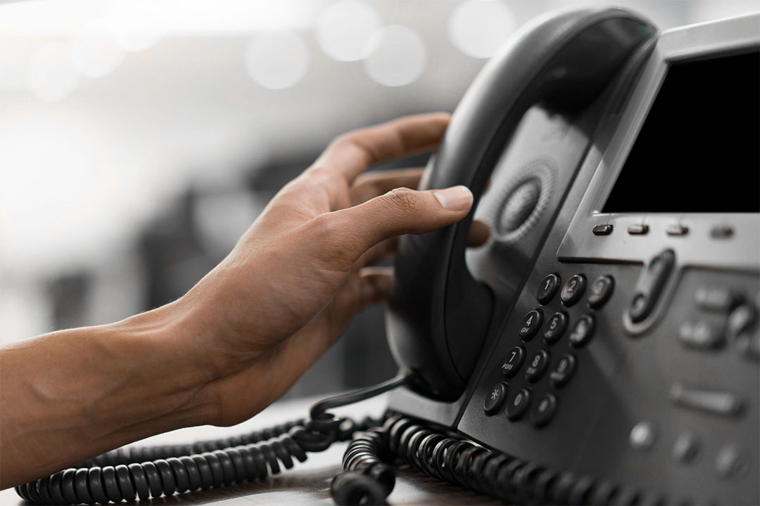 A closeup of a nurse reaching for an office phone.
