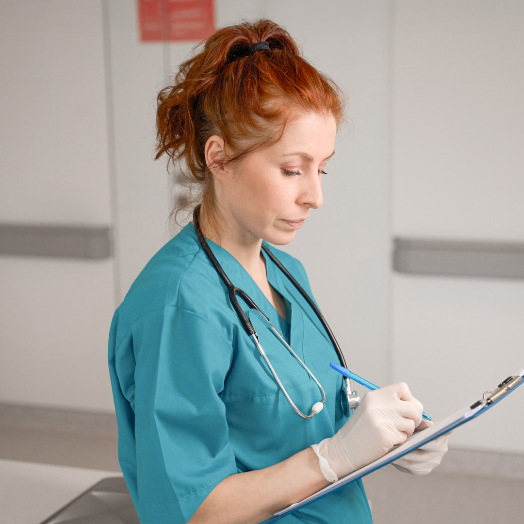 A female nurse filling out a form on a clipboard. 